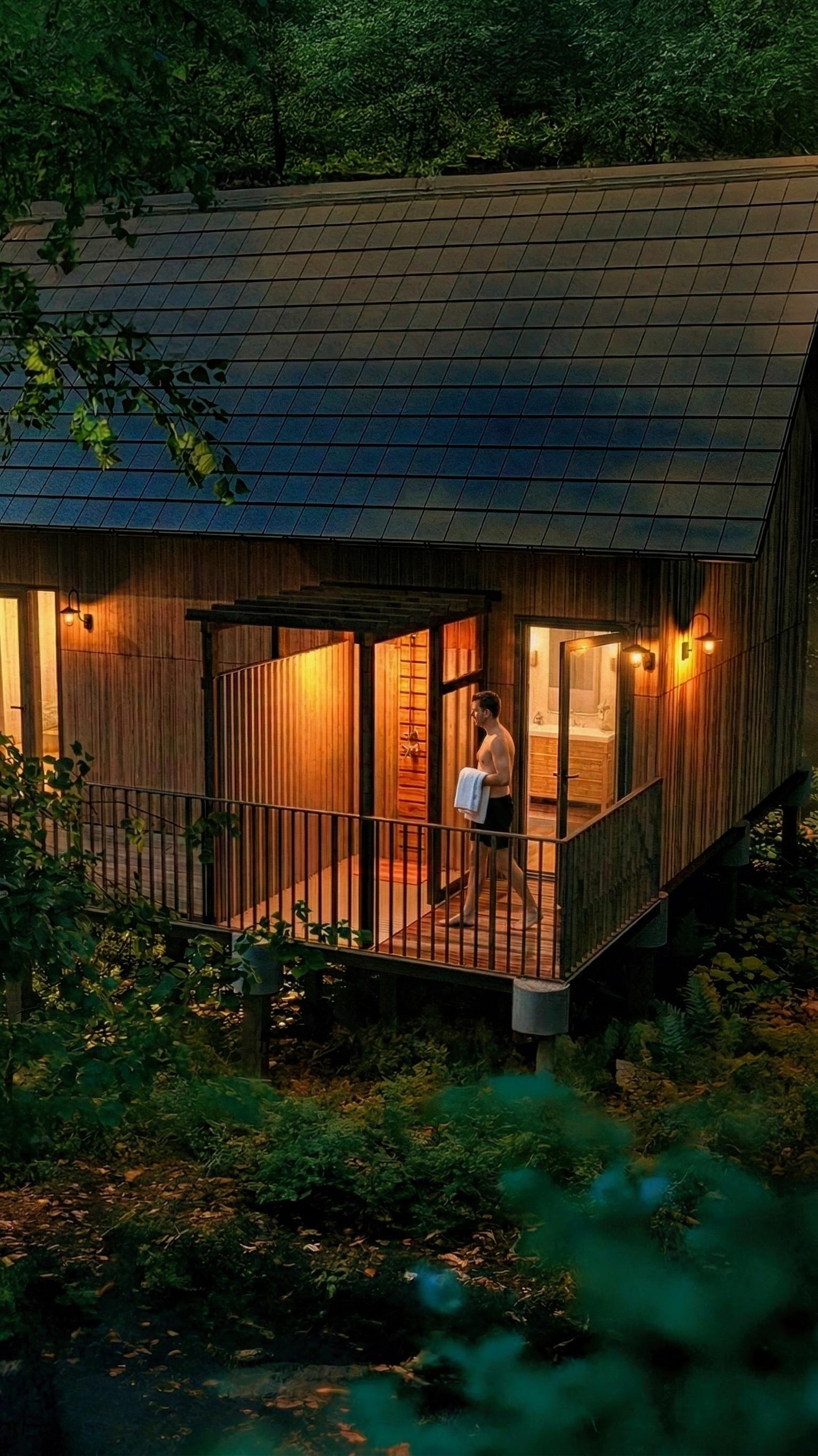 Guest stepping onto a lantern-lit treehouse deck at night